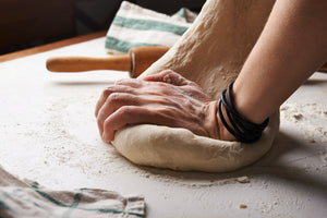 Closeup of a baker kneeding bread on a floured surface